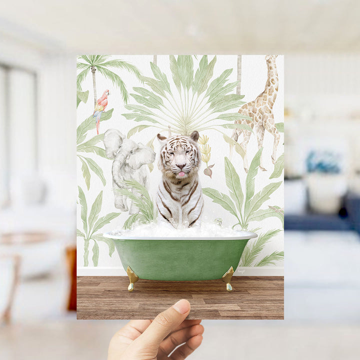 A hand holds up a framed image depicting a tiger sitting in a green bathtub surrounded by tropical foliage, including a giraffe and palm trees.