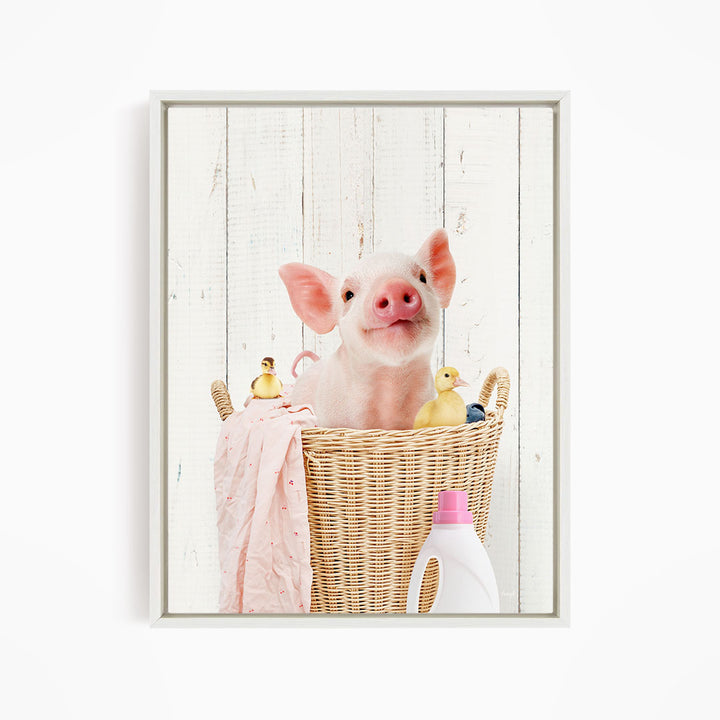 A cute pig sitting in a wicker basket filled with rubber ducks, surrounded by a pink blanket and a bottle of detergent.