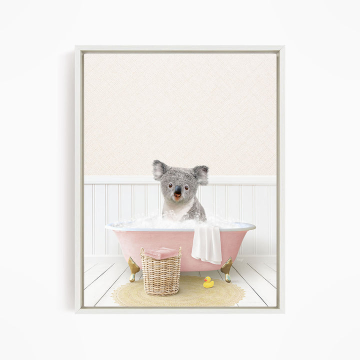 A koala bear sitting in a pink bathtub filled with water, surrounded by a yellow rubber duck and a wicker basket.