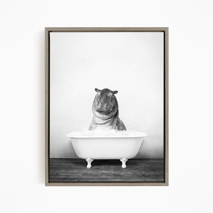 A black and white photograph of a hippopotamus sitting in a bathtub filled with water.