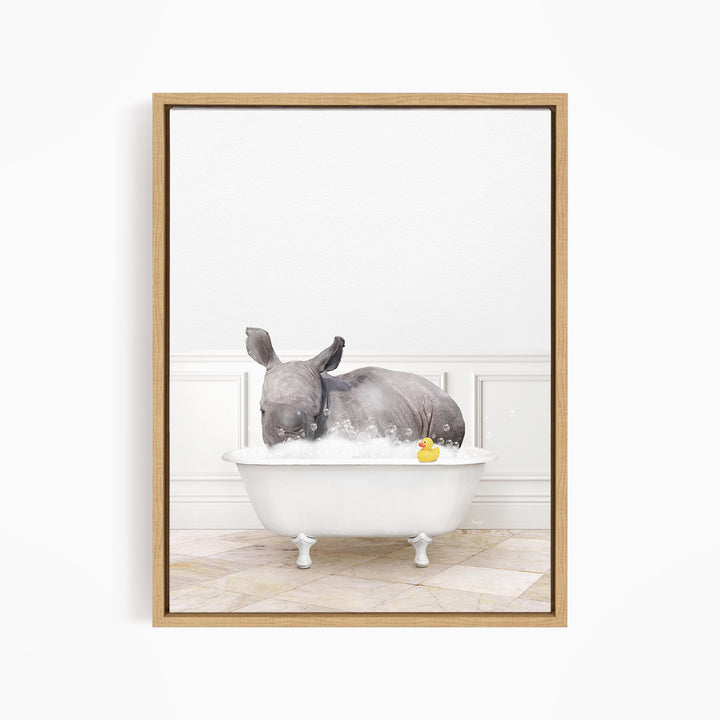A rhinoceros is sitting in a white bathtub filled with water, surrounded by bubbles, and holding a yellow rubber duck.