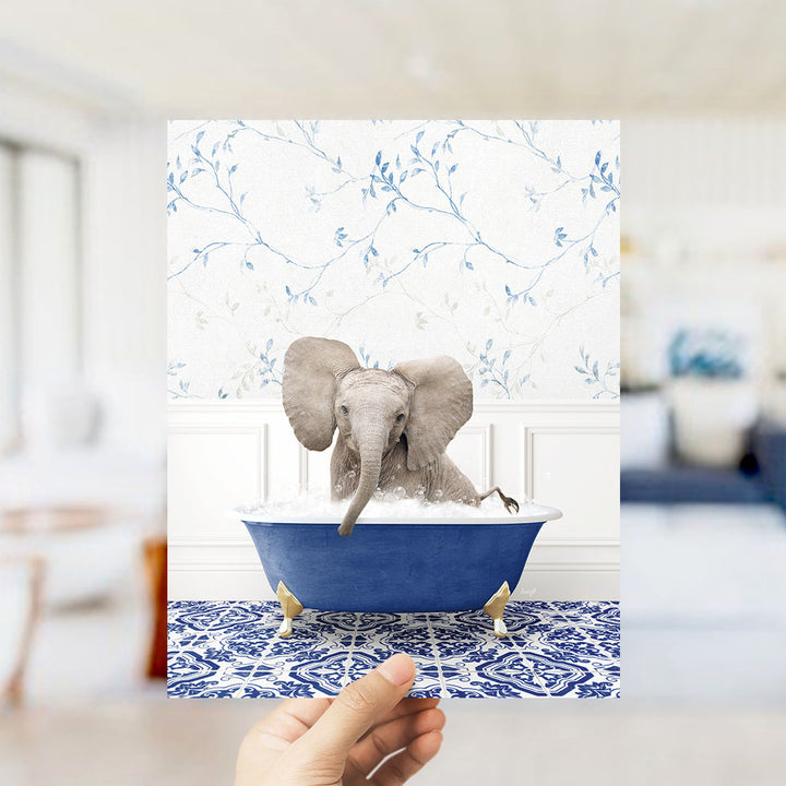 A small elephant sitting in a blue bathtub filled with water, surrounded by a blue and white floral patterned wall.
