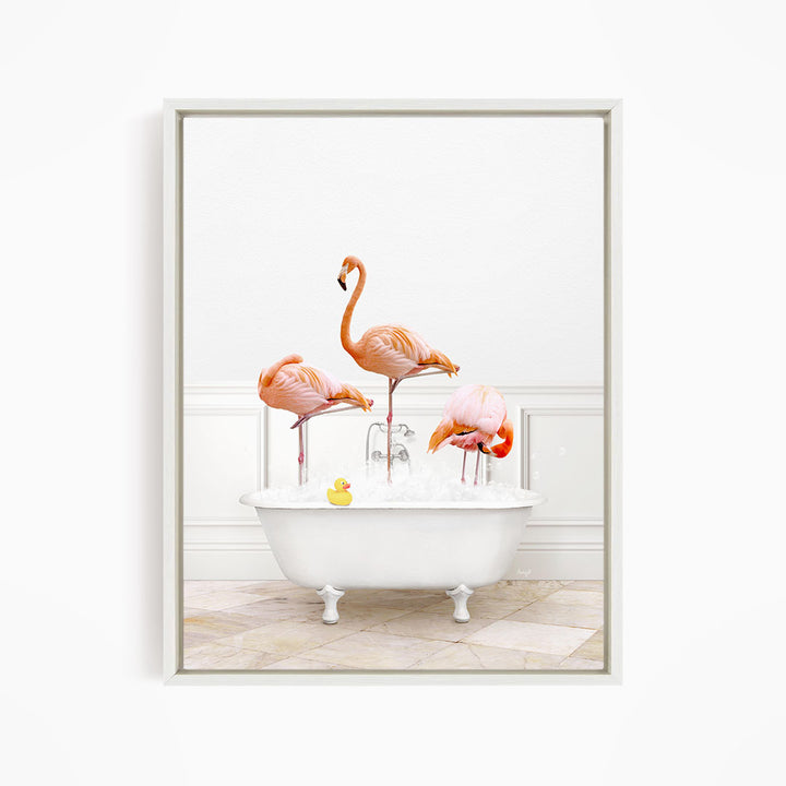 A framed image depicting three flamingos standing in a white bathtub filled with water, with a yellow rubber duck floating in the water.
