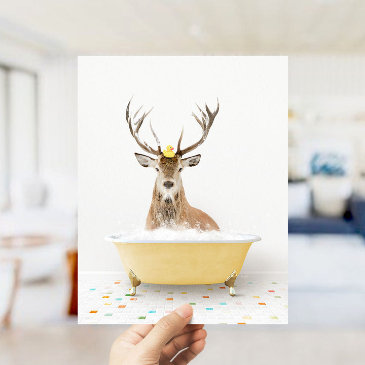 A deer with antlers is sitting in a yellow bathtub filled with bubbles, with a rubber duck floating on its head.