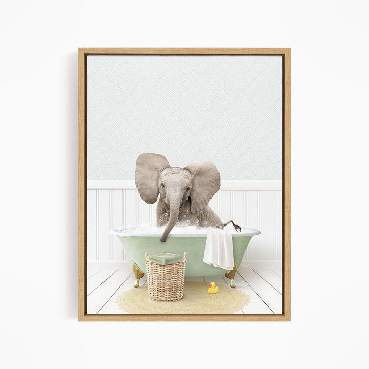 A baby elephant sitting in a green bathtub filled with water, surrounded by a basket of toys and a yellow rubber ducky.