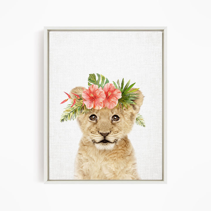 A young lion cub wearing a floral headpiece with pink and green flowers and leaves.