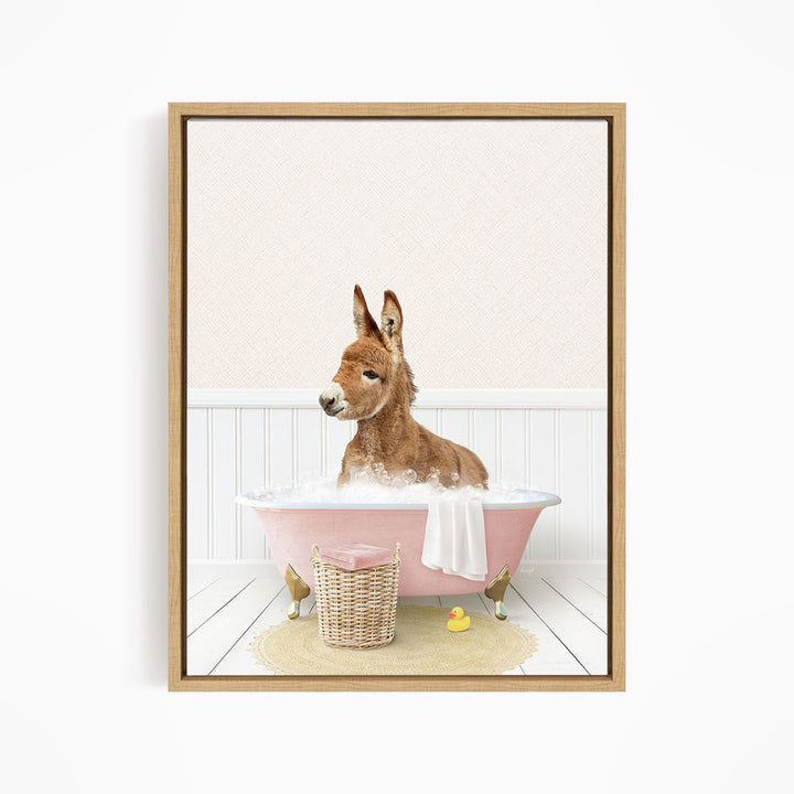 A donkey is sitting in a pink bathtub filled with bubbles, surrounded by a yellow rubber duck and a basket.