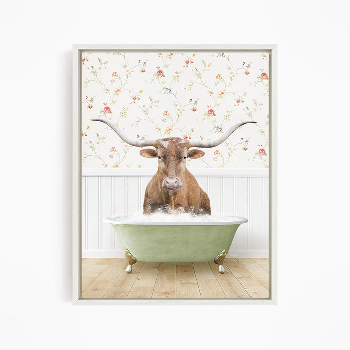 A brown steer with large horns is sitting in a green bathtub filled with water, with a floral wallpaper in the background.