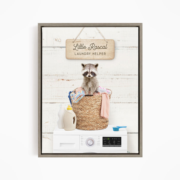 A raccoon sitting in a laundry basket, with a sign that says "Little Racal Laundry Helper" hanging above it.