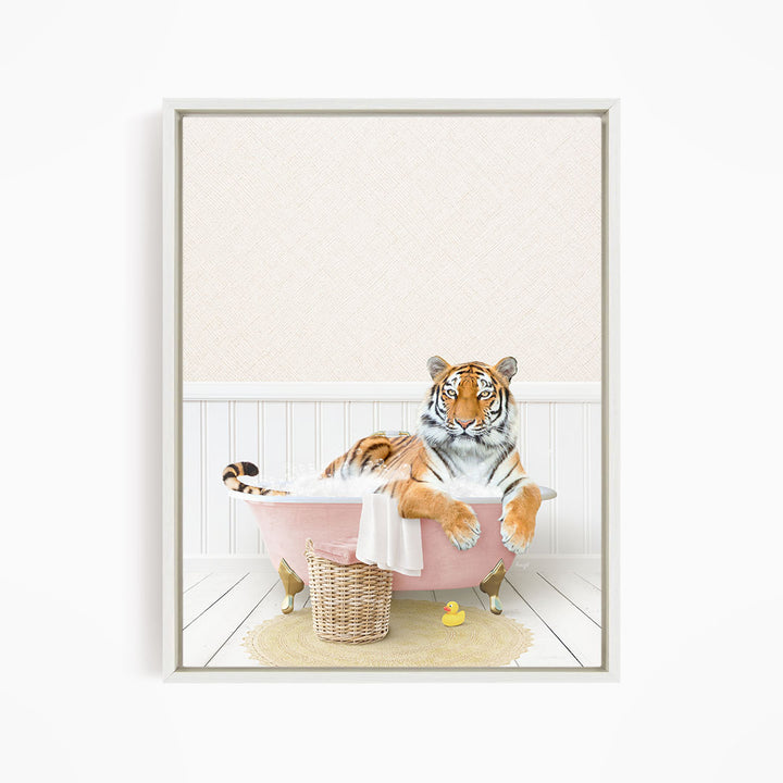 A tiger is sitting in a pink bathtub, surrounded by a yellow rubber duck and a basket.
