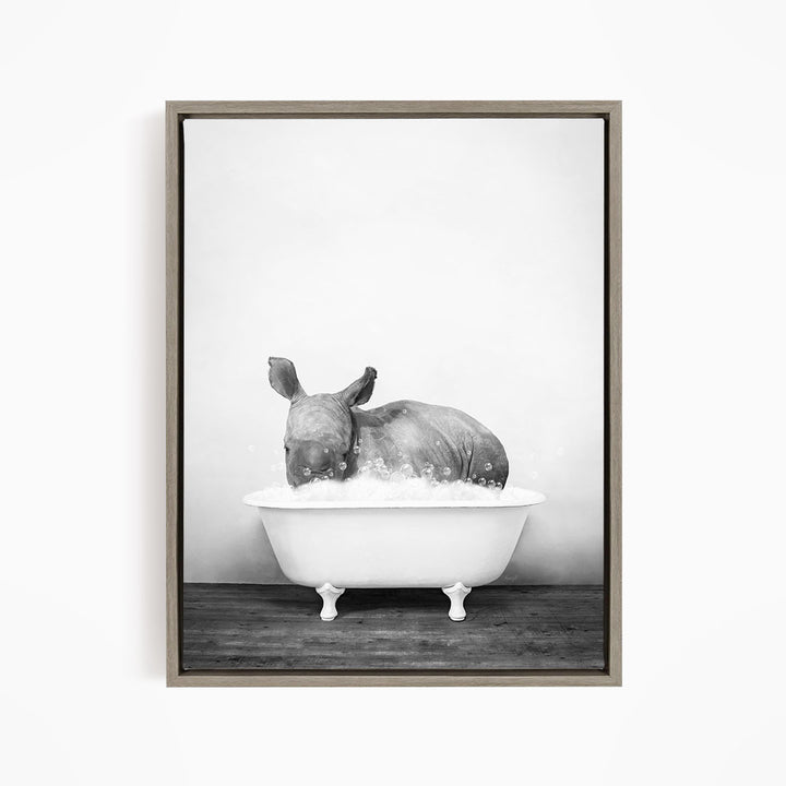 A rhinoceros is sitting in a bathtub filled with water, creating a whimsical and playful scene.