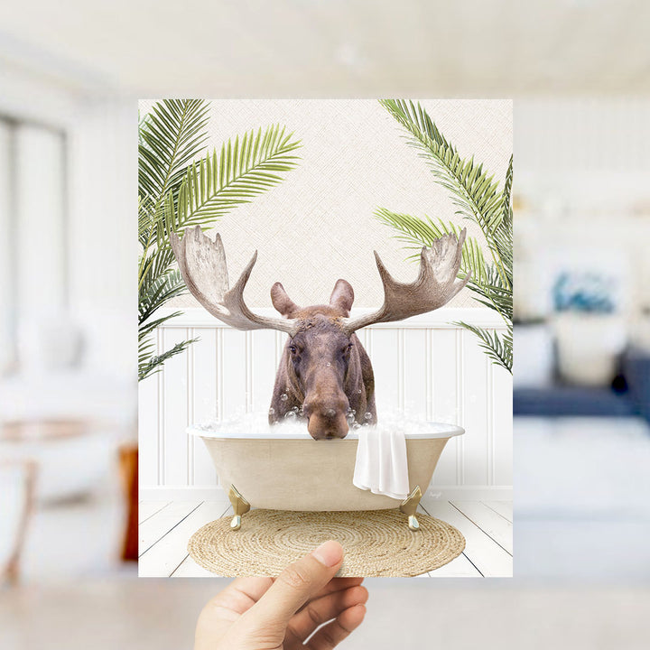 A moose with large antlers is sitting in a bathtub filled with water, surrounded by green leaves.