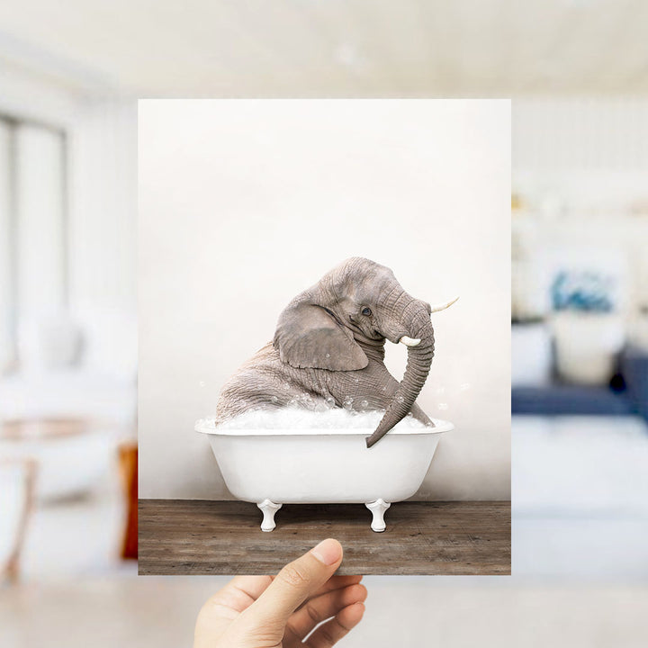 A gray elephant sitting in a white bathtub filled with water, with bubbles around it, in a room with a white wall and a blue object in the background.