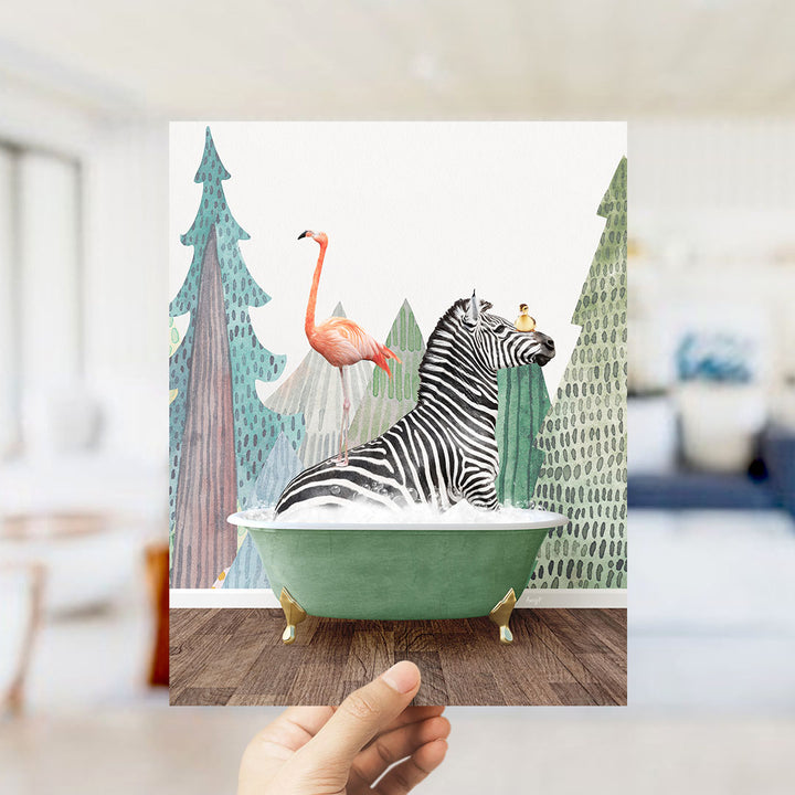 A hand holds up a framed image depicting a zebra sitting in a green bathtub, with a flamingo standing on its back and a bird perched on its head.