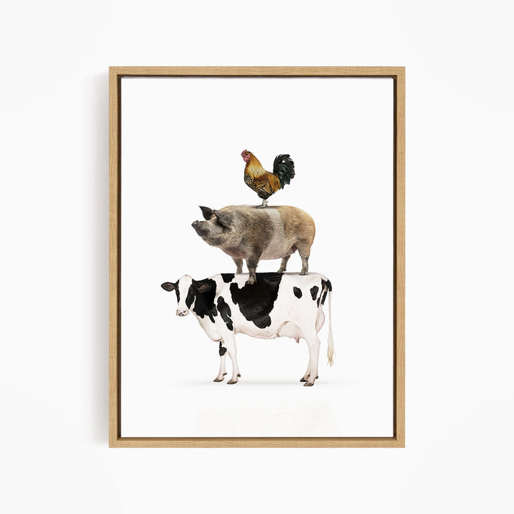 A framed illustration depicting a rooster perched on top of a cow, with a pig standing below.