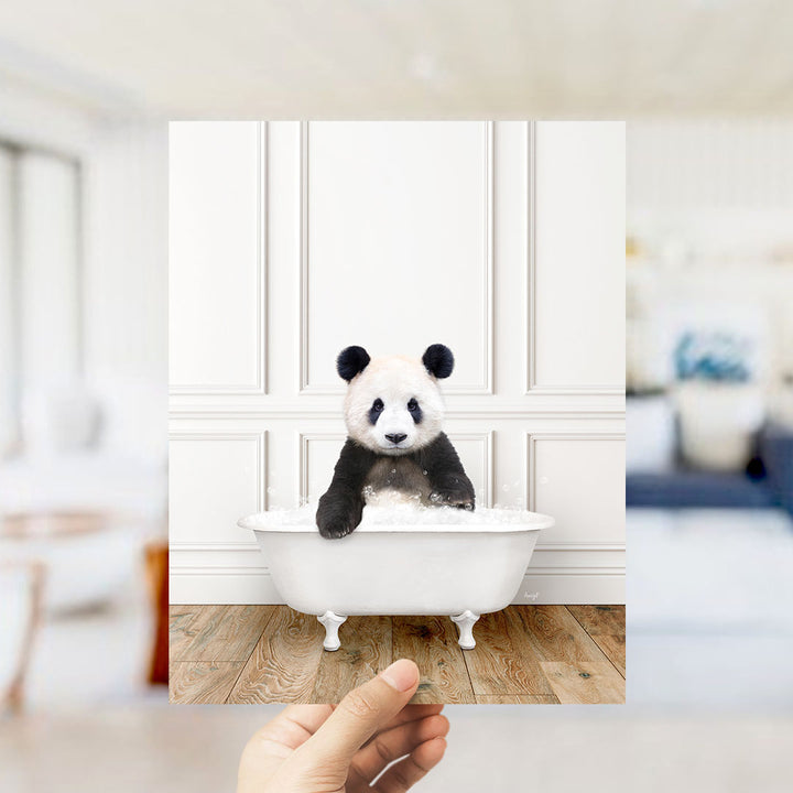 A panda bear sitting in a white bathtub, surrounded by a blurred background of a living room.