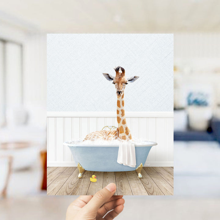 A giraffe sitting in a blue bathtub filled with bubbles, with a towel draped over its neck.