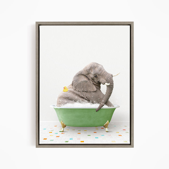 A gray elephant is sitting in a green bathtub, with a yellow rubber duck floating on its back.