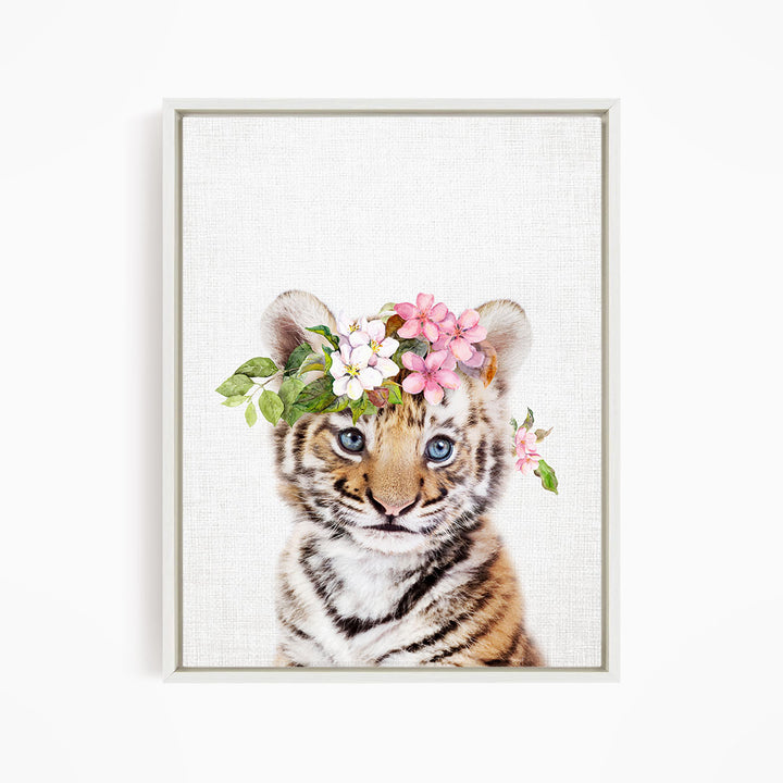 A young tiger cub wearing a floral crown of pink and white flowers.