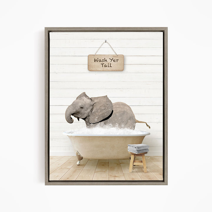 A gray elephant is sitting in a bathtub filled with water, with a wooden sign above it that says "Wash Your Tail".