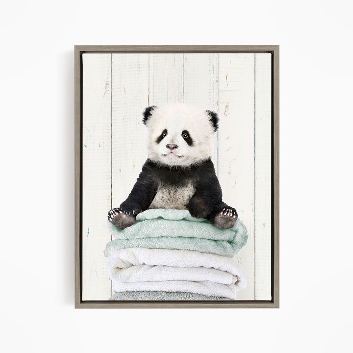 A panda bear sitting on a stack of towels, with a white background.