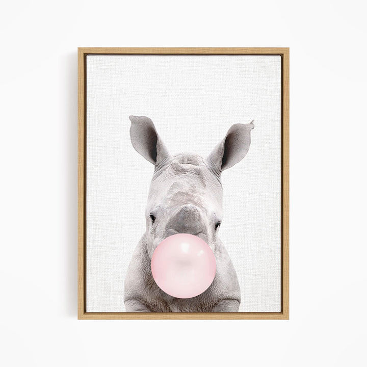 A rhinoceros blowing a pink bubble with its mouth.