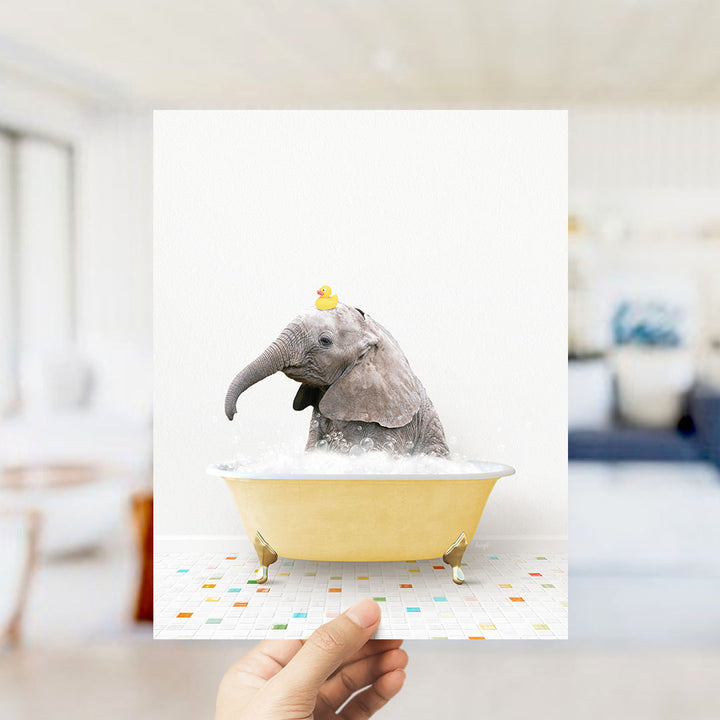 A small elephant is sitting in a yellow bathtub, with a yellow rubber duck perched on its head.