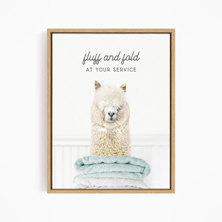A fluffy alpaca sitting on a stack of light blue towels, with the text "fluff and fold at your service" written above the image.