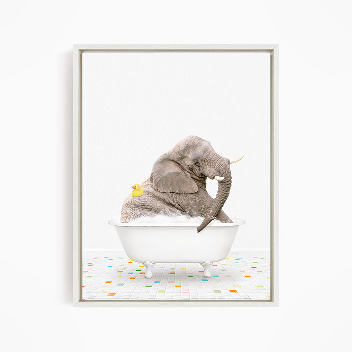 A gray elephant is sitting in a white bathtub, with a yellow rubber duck floating on the water.