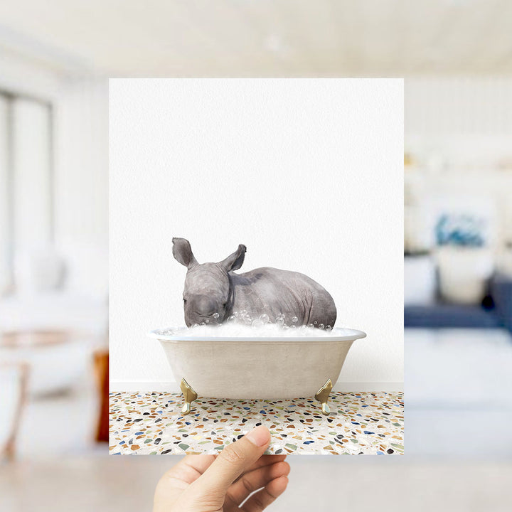 A rhinoceros is sitting in a bathtub filled with water, creating a whimsical and playful scene.