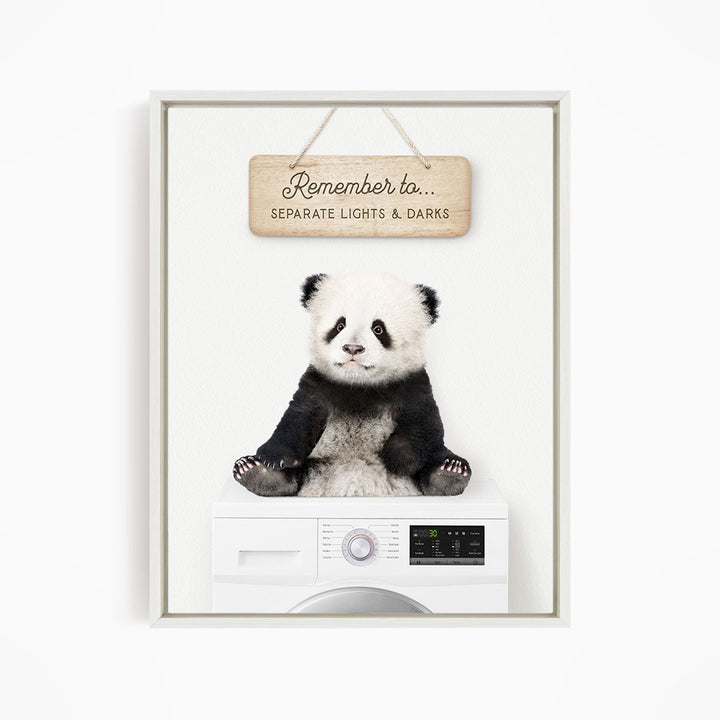 A panda bear sitting on top of a washing machine, with a wooden sign above that says "Remember to separate lights & darks".