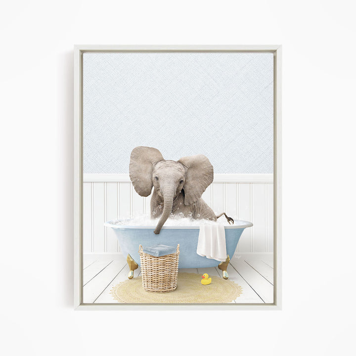 A gray elephant is sitting in a blue bathtub filled with water, surrounded by a yellow rubber duck and a basket.