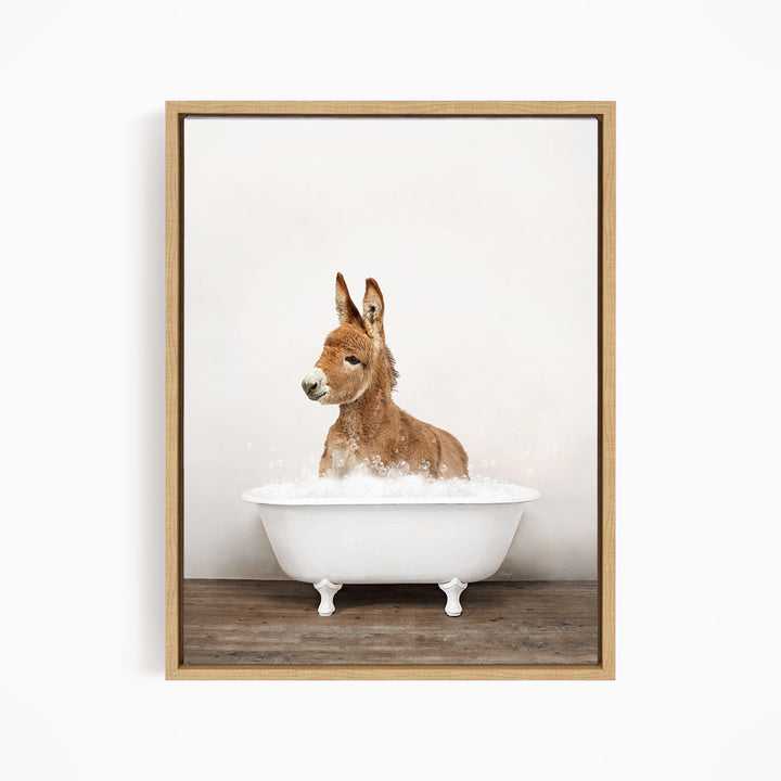 A donkey is sitting in a white bathtub filled with bubbles, looking directly at the camera.