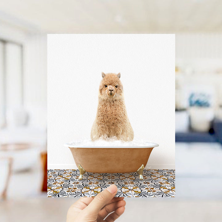 A fluffy brown alpaca sitting in a bathtub filled with bubbles, with a hand holding the image up to the camera.
