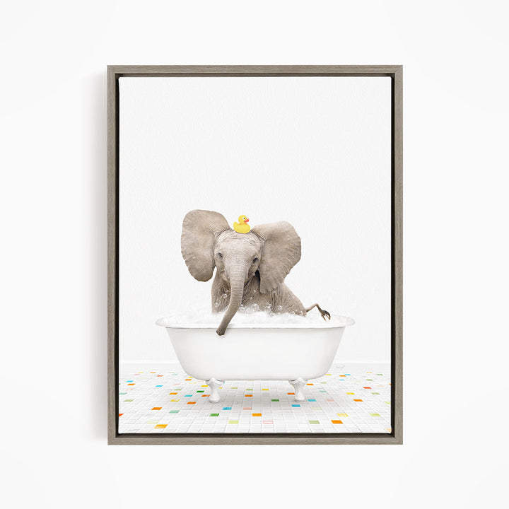 A gray elephant is sitting in a white bathtub filled with water, with a yellow rubber duck floating on its head.