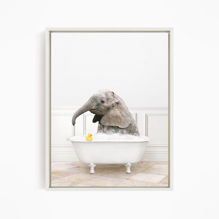 A baby elephant sitting in a white bathtub, with a yellow rubber duck floating in the water.