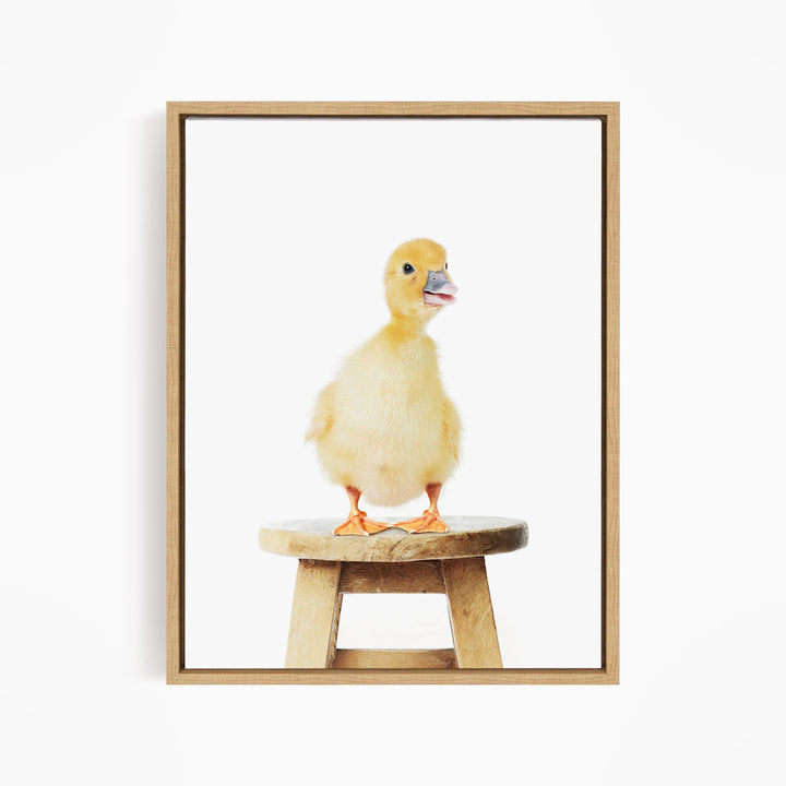 A small yellow duck standing on a wooden stool.