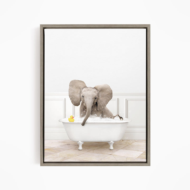 A gray elephant is sitting in a white bathtub, with a yellow rubber duck floating on the water.