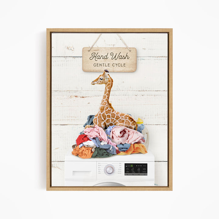 A giraffe sitting on a pile of laundry, with a sign above that says "Hand Wash Gentle Cycle".
