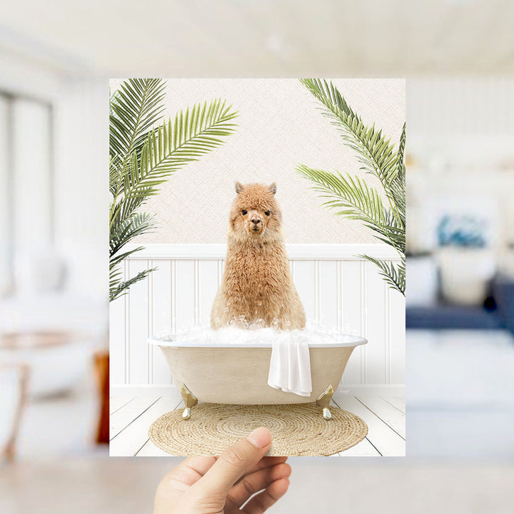 A hand holds up a framed image of a fluffy brown dog sitting in a bathtub filled with bubbles, surrounded by green palm leaves.