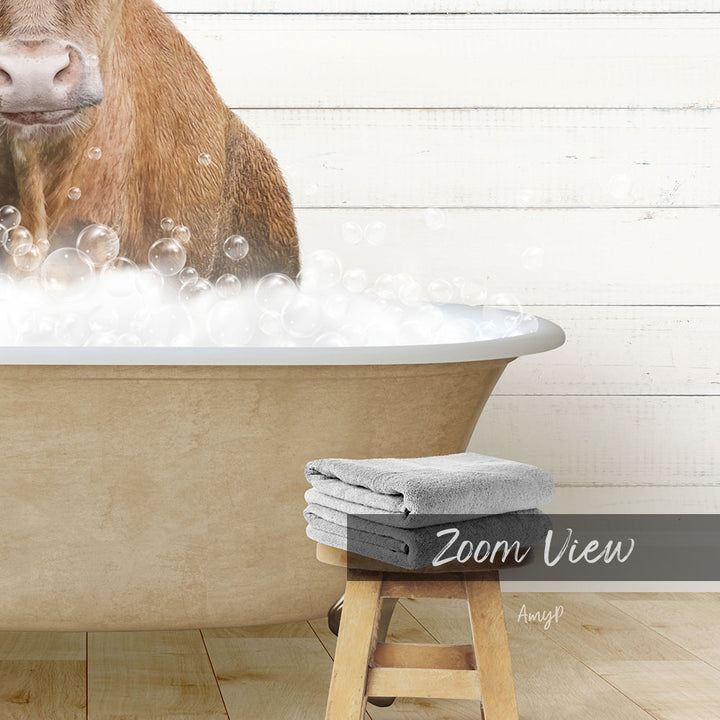 A cow is sitting in a bathtub filled with bubbles, with a towel and stool visible in the foreground.