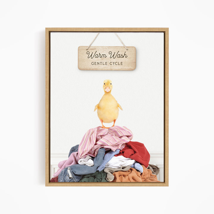 A yellow duck standing on a pile of clothes, with a wooden sign above that reads "Warm Wash Gentle Cycle".