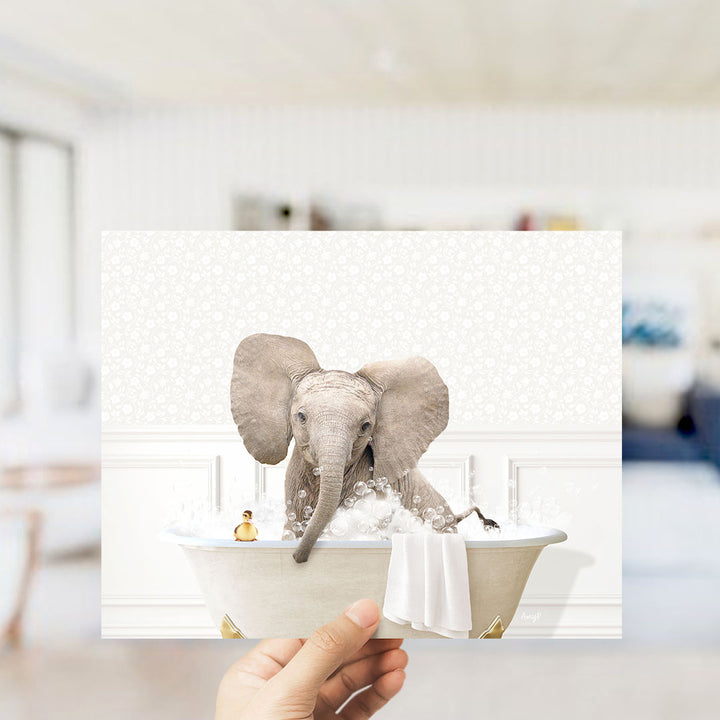 A hand holds up a collage of images depicting an elephant sitting in a bathtub, surrounded by bubbles and a small yellow toy.