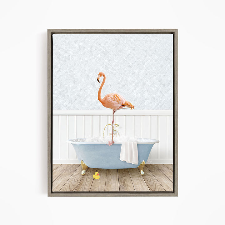 A pink flamingo stands on the edge of a blue bathtub filled with water, with a towel and rubber duckies nearby.