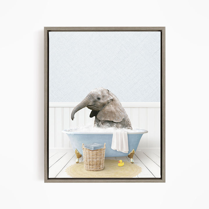 A gray elephant is sitting in a blue bathtub filled with water, surrounded by a yellow rubber duck and a basket.