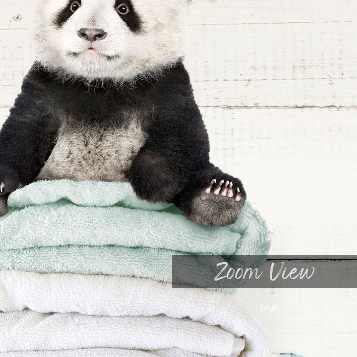 A panda bear sitting on a stack of light blue towels, with a white background.