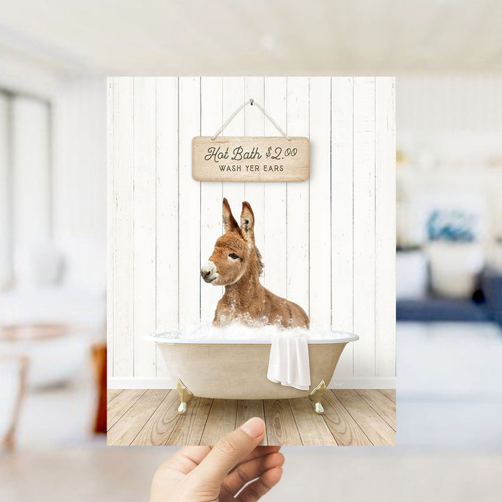 A donkey is sitting in a bathtub filled with water, with a sign above it that says "Hot Bath $2.00 WASH YOUR EARS".