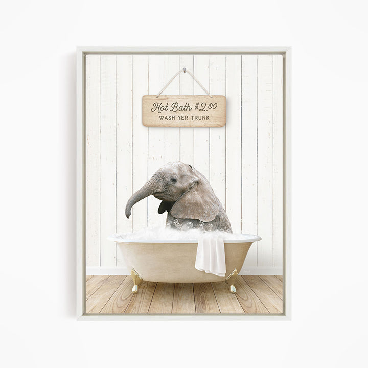 A gray elephant is sitting in a white bathtub filled with water, with a wooden sign above it that reads "Hot Bath $2.00 WASH YER TRUNK."