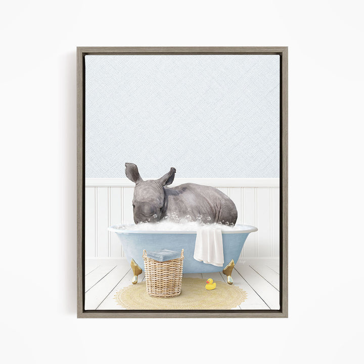 A rhinoceros is sitting in a blue bathtub filled with water, surrounded by a yellow rubber duck and a basket.