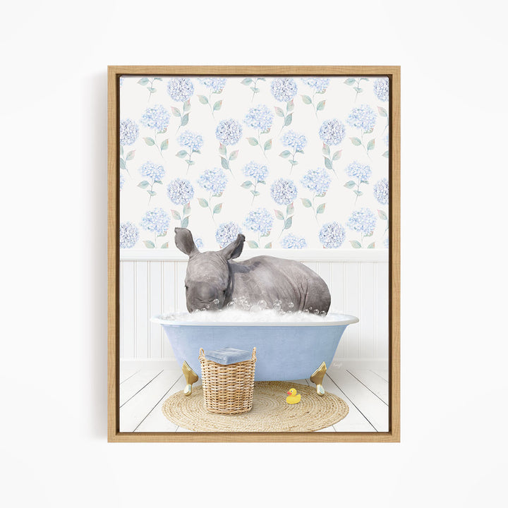 A rhinoceros is sitting in a blue bathtub filled with water, surrounded by a wicker basket and yellow rubber ducks.